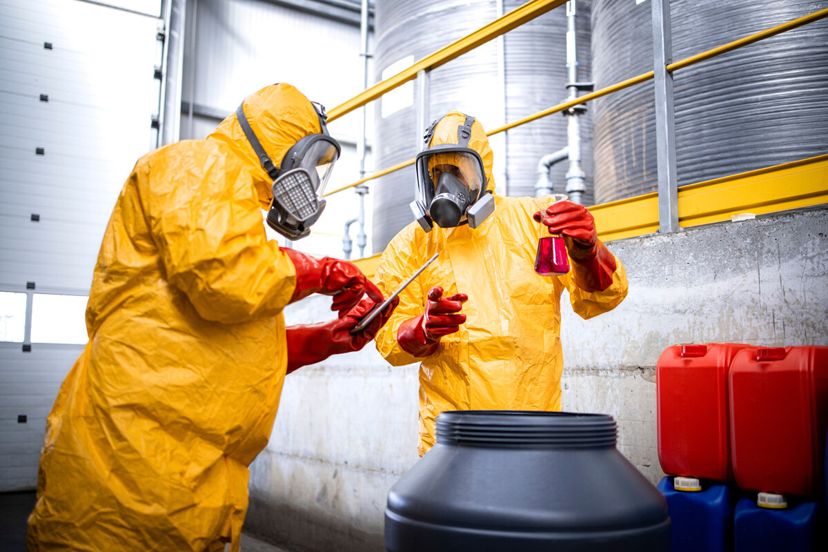 Two workers in protective equipment checking chemicals